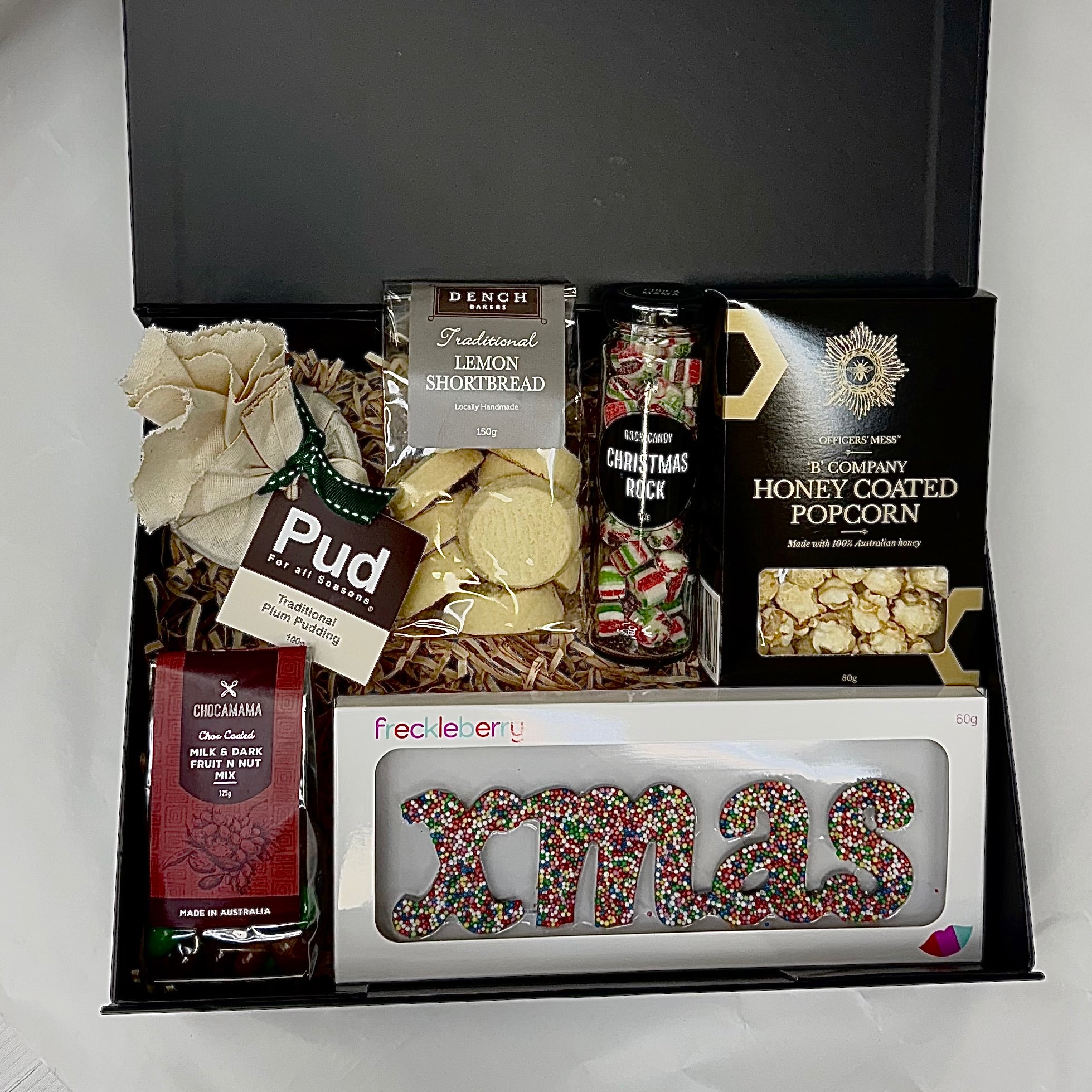 Christmas Gift basket with various items including a box of chocolates, cookies, and a decorative 'XMAS' letter set.